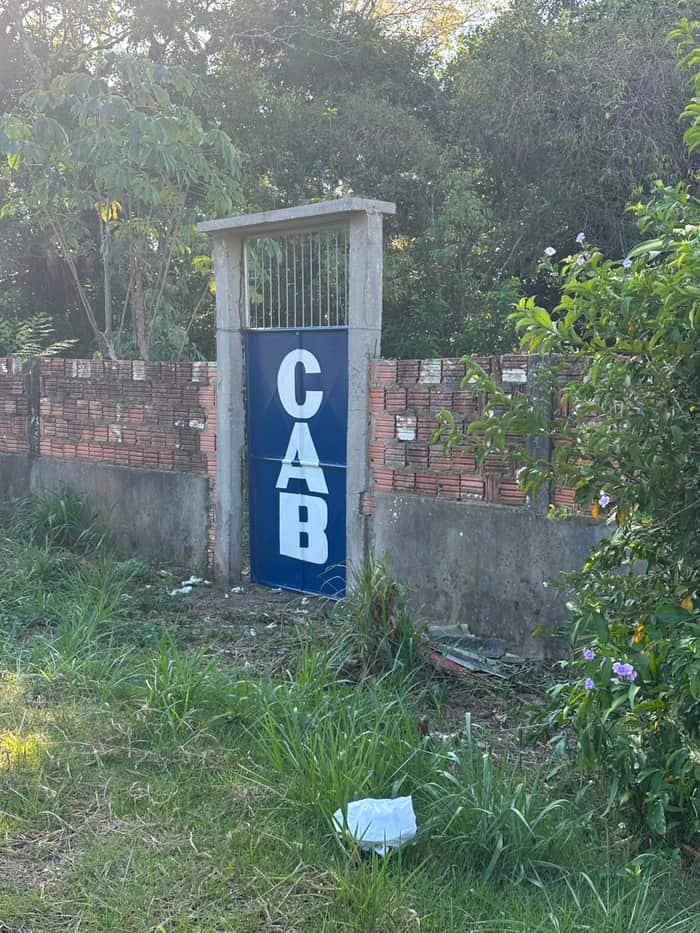 Portão de pedestres azul com a marca CAB, integrado ao muro do terreno